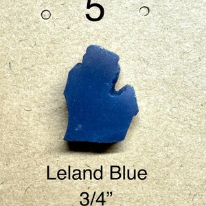 May include: A vibrant blue Leland Blue stone, shaped like the state of Michigan. The stone is approximately 3/4 inch in size. The number 5 is above the stone.