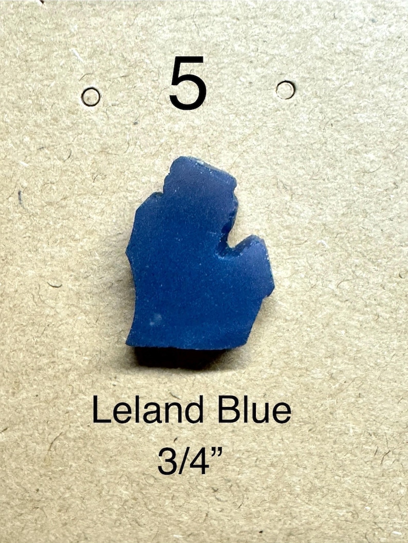 May include: A vibrant blue Leland Blue stone, shaped like the state of Michigan. The stone is approximately 3/4 inch in size. The number 5 is above the stone.