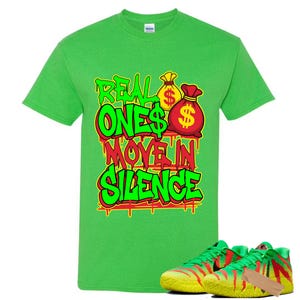 May include: A bright green t-shirt with the text "REAL ONES MOVE IN SILENCE" in a graffiti style design, featuring money bag graphics. Below the shirt are green and yellow sneakers with red accents.