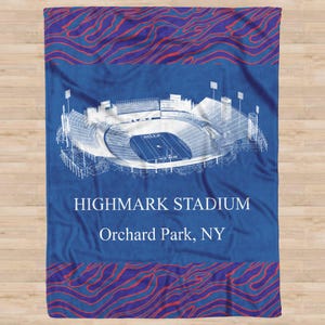 May include: Blue stadium blanket featuring a white architectural drawing of Highmark Stadium. The blanket has a blue background with red and blue patterned borders and the text "HIGHMARK STADIUM Orchard Park, NY."