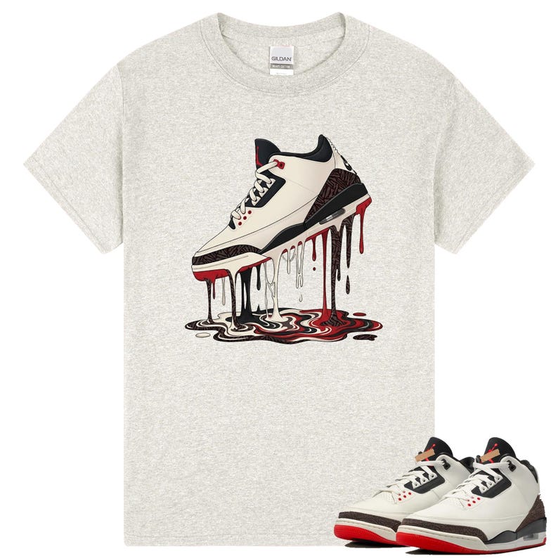 May include: A light grey t-shirt with a graphic of a white, black, and red trainer with a dripping design. A pair of matching trainers with red soles are displayed below the shirt.