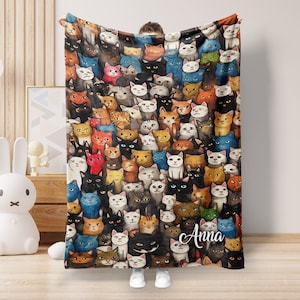 May include: A vibrant blanket displaying a multitude of cat illustrations in diverse colours. The cats are shown in black, white, ginger, and grey. The blanket has the name "Anna" written on it in white script.