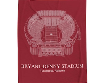 Op de afbeelding: Een karmozijnrode stadiondeken met een gedetailleerde witte architectonische weergave van het Bryant-Denny Stadium in Tuscaloosa, Alabama. De naam en locatie van het stadion staan ​​wit onderaan. De deken is rechthoekig.