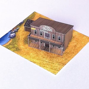 May include: A paper model of a Western saloon with a brown wooden facade and a sign that reads "The Saloon". The model is sitting on a brown and yellow paper background.