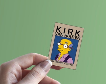 May include: A close-up of a card with a cartoon image of a man with a yellow face, blue shirt, and glasses. The text on the card reads "KIRK VAN HOUTEN".