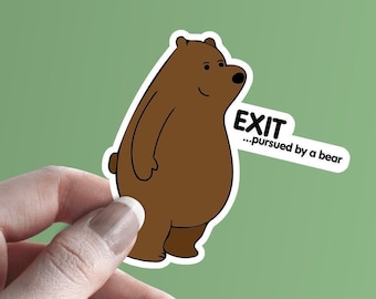 Peut inclure: Un autocollant représentant un ours brun avec le texte "EXIT - pursued by a bear" sur un fond vert.