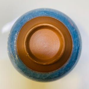 Puede incluir: Un cuenco de cer&aacute;mica con exterior azul e interior marr&oacute;n. La superficie azul tiene un efecto craquelado. El interior del cuenco es de color marr&oacute;n c&aacute;lido. El cuenco probablemente se utiliza para servir alimentos o como objeto decorativo.