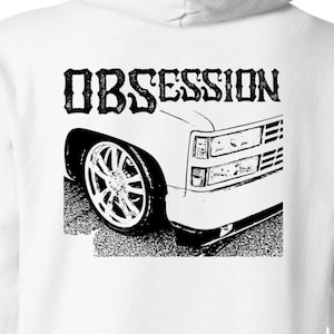 May include: White hooded sweatshirt with a black and white graphic of a truck with the word "OBSESSION" printed above it.