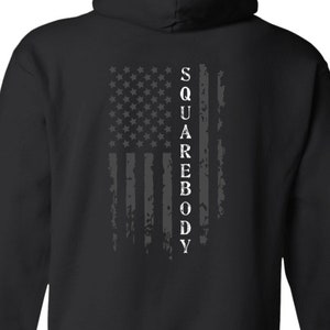 May include: Black hooded sweatshirt with a distressed American flag design and the text "SQUAREBODY" printed vertically down the center of the flag.