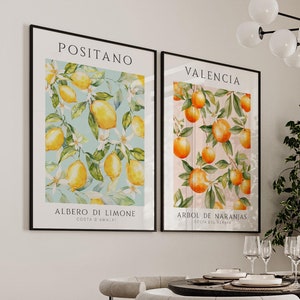 Könnte beinhalten: Zwei gerahmte botanische Drucke mit Aquarell-Illustrationen von Zitronen und Orangen. Die Drucke sind mit "Positano" und "Valencia" betitelt und zeigen die italienischen und spanischen Namen für die Früchte. Die Drucke hängen an einer weißen Wand in einem Esszimmer.