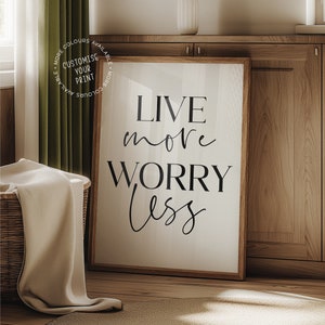 Puede incluir: Una impresión enmarcada con las palabras "LIVE more WORRY less" en escritura negra. La impresión está en un marco de madera y se muestra sobre un fondo neutro. La imagen también incluye el texto "PROFESSIONAL GRADE - PREMIUM SATIN PHOTOPAPER".