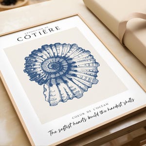 K&ouml;nnte beinhalten: Eine blaue und wei&szlig;e Illustration einer Muschel mit dem Text "Exposition de C&ocirc;ti&egrave;re" und "The softest hearts build the hardest shells Coeur de l'oc&eacute;an".