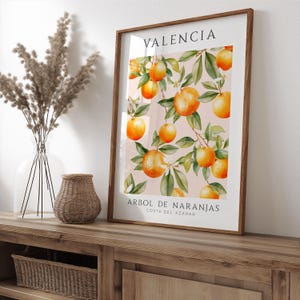 May include: A framed print with a watercolor illustration of orange trees with ripe oranges. The print has the text "VALENCIA" and "ARBOL DE NARANJAS COSTA DEL AZAHAR" in black.