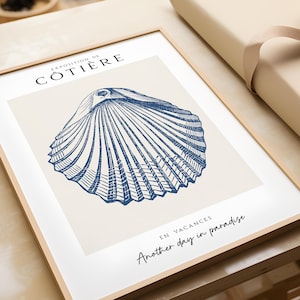 K&ouml;nnte beinhalten: Ein gerahmter Druck mit einer blauen und wei&szlig;en Illustration einer Muschel. Der Text "Exposition de C&ocirc;ti&egrave;re" befindet sich oben auf dem Druck. Der Text "En Vacances Another day in paradise" befindet sich unten auf dem Druck.