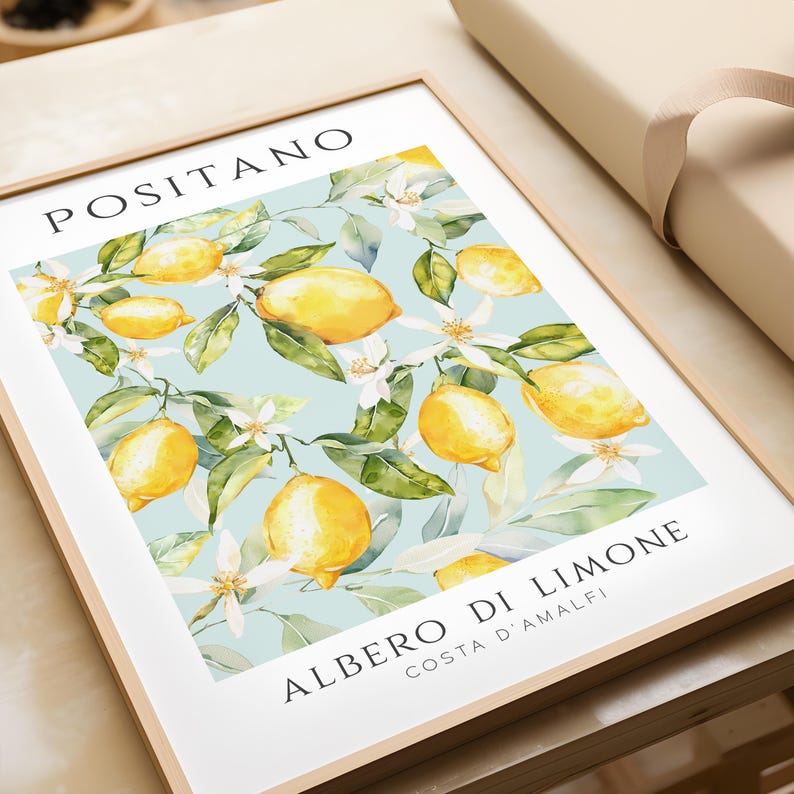 May include: A framed print with a watercolor illustration of a lemon tree with yellow lemons and white blossoms on a light blue background. The text "POSITANO" is at the top of the print and "ALBERO DI LIMONE COSTA D'AMALFI" is at the bottom.