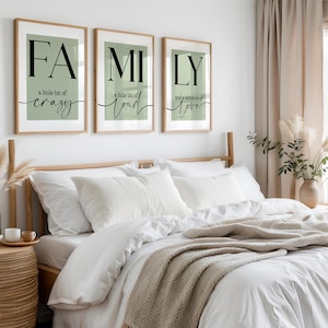 May include: Three framed prints spelling "FAMILY" with the phrases "a little bit of crazy", "a little bit of loud", and "and a whole lot of love" in black script. The prints hang above a bed with white bedding and a beige throw.