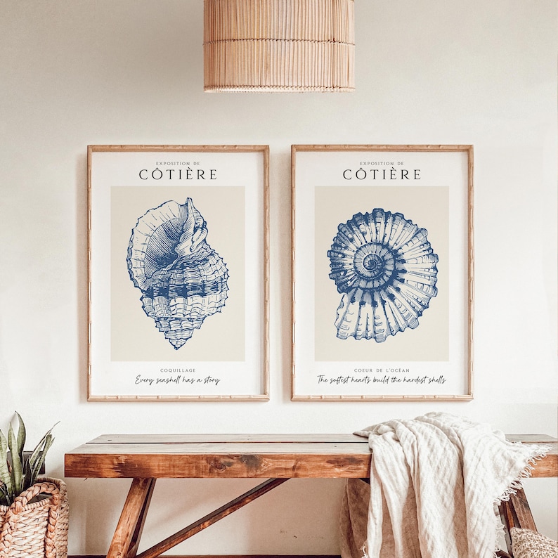 Pode incluir: Duas impress&otilde;es emolduradas com ilustra&ccedil;&otilde;es azuis de conchas marinhas sobre um fundo bege. O texto nas impress&otilde;es diz "Exposition de C&ocirc;ti&egrave;re" e "Coquillage" e "Every seashell has a story" e "Coeur de l'Ocean" e "The softest hearts build the hardest shells".