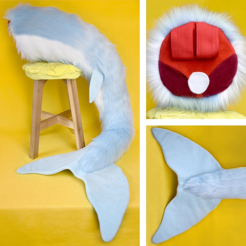 May include: A whimsical, light blue and white plush whale tail prop, with a matching headpiece. The tail is made of soft, faux fur and fabric, and is designed to be worn. The headpiece features red straps and a white fur trim.