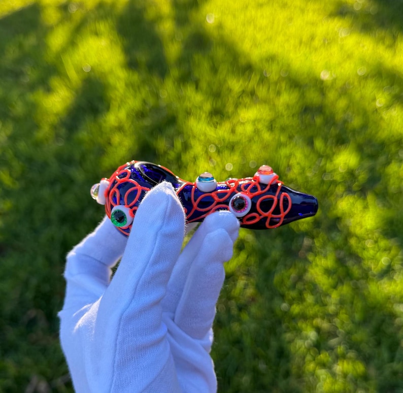 May include: A blue glass pipe with a red and orange swirl design and multiple googly eyes.