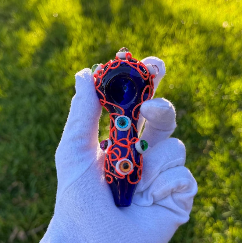 May include: A blue glass pipe with a bright orange wire design and colorful glass eyes.