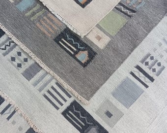 Könnte beinhalten: Geometrisch gemusterte Teppiche in Grau-, Beige- und gedeckten Farbtönen. Die Teppiche weisen rechteckige und quadratische Formen mit abstrakten Designs auf. Die Kanten haben ein Fransen Detail, das dem Textil Textur verleiht.