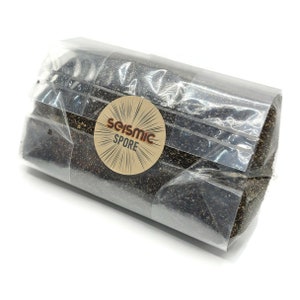 May include: A clear plastic bag filled with black and gold glitter. The bag has a brown label with the text "Seismic Spore" in a white circle with a sunburst design.