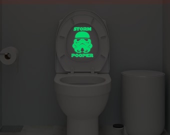 May include: A white toilet with a glow-in-the-dark toilet seat cover featuring a Star Wars Stormtrooper helmet and the text "Storm Pooper".