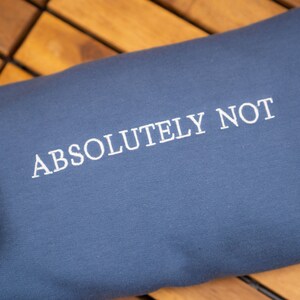 May include: A dark blue sweatshirt with the text "ABSOLUTELY NOT" embroidered in white.