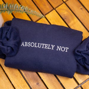 May include: A navy blue sweatshirt with the text "ABSOLUTELY NOT" embroidered in white.