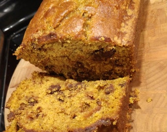 Puede incluir: Un pan de calabaza con chispas de chocolate, cortado en rebanadas sobre una tabla de cortar de madera.