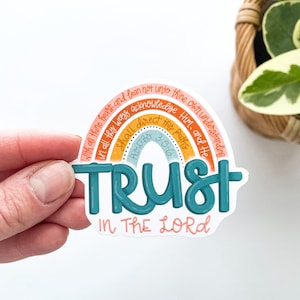 May include: A rainbow-colored sticker with the words "TRUST IN THE LORD" and the Bible verse "Proverbs 3:5-6" written in a handwritten font. The sticker is on a white background.