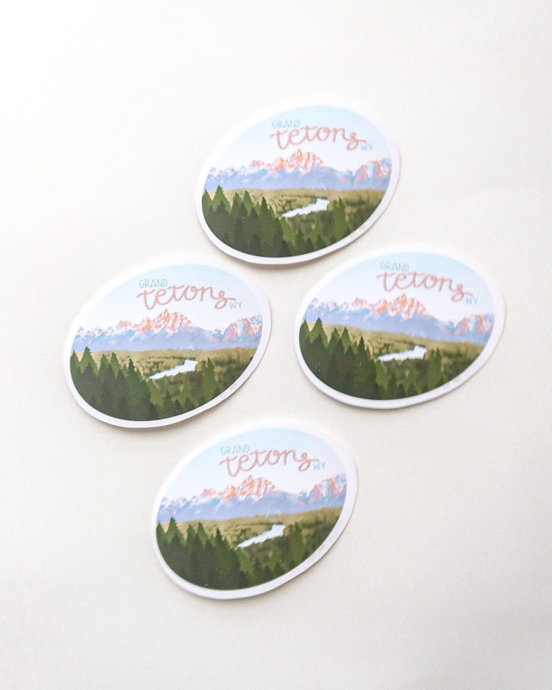 Pode incluir: Quatro adesivos ovais com uma cordilheira e um rio em primeiro plano. O texto "GRAND TETONS WY" est&aacute; escrito em it&aacute;lico em cada adesivo.
