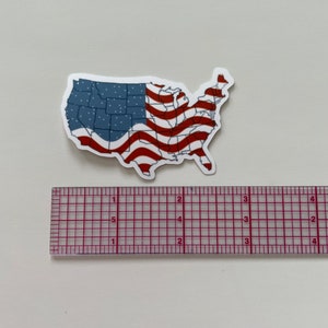 K&ouml;nnte beinhalten: Ein Aufkleber der Vereinigten Staaten von Amerika mit einem rot-wei&szlig;-blauen amerikanischen Flaggen-Design. Der Aufkleber ist etwa 7,6 cm breit.