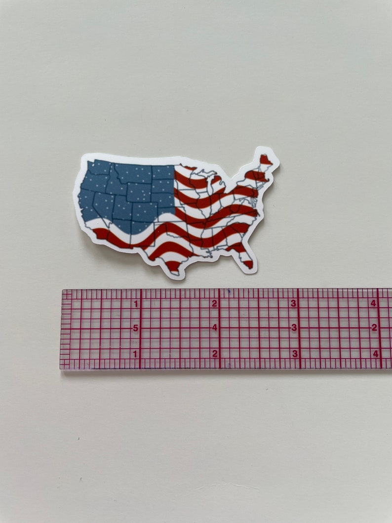K&ouml;nnte beinhalten: Ein Aufkleber der Vereinigten Staaten von Amerika mit einem rot-wei&szlig;-blauen amerikanischen Flaggen-Design. Der Aufkleber ist etwa 7,6 cm breit.