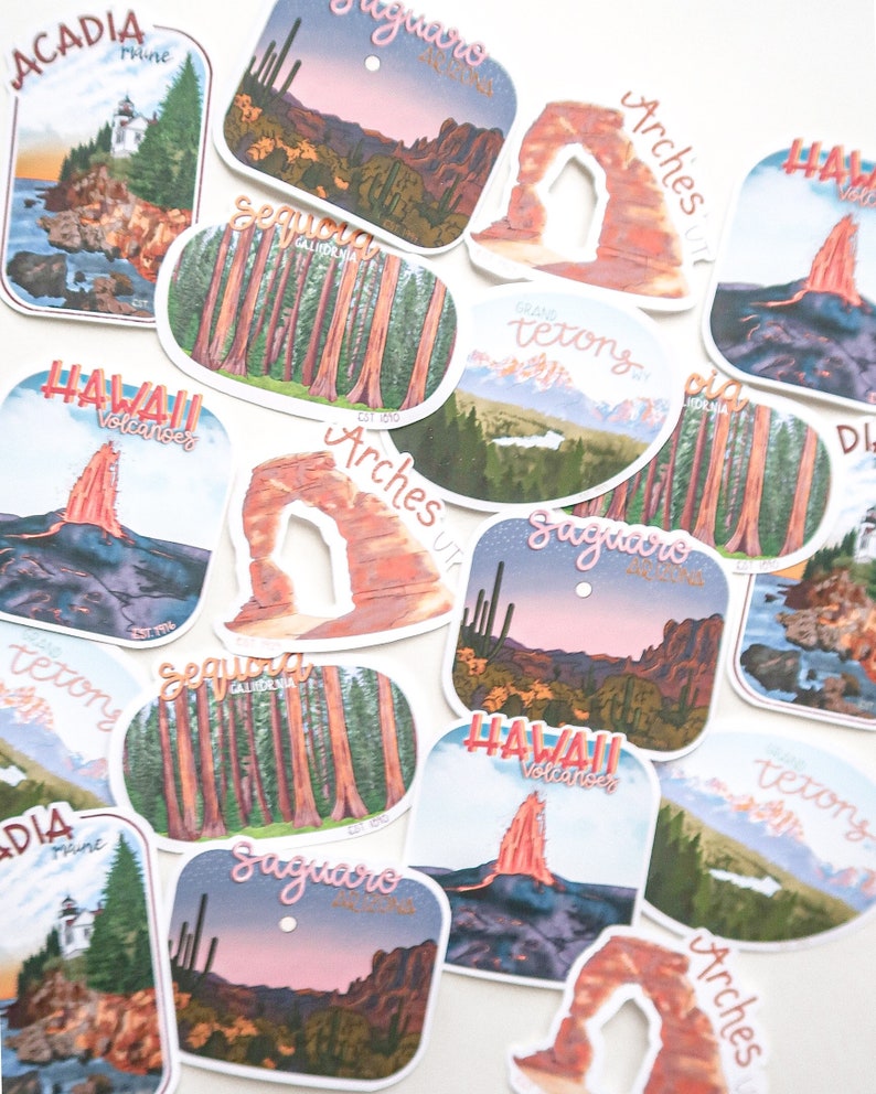 Pode incluir: Uma cole&ccedil;&atilde;o de adesivos coloridos que representam v&aacute;rios parques nacionais e monumentos. Os adesivos s&atilde;o impressos com ilustra&ccedil;&otilde;es de locais emblem&aacute;ticos como o Parque Nacional Arches, o Parque Nacional Yosemite e o Parque Nacional dos Vulc&otilde;es do Hava&iacute;. Cada adesivo tem o nome do parque e sua localiza&ccedil;&atilde;o.