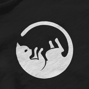 May include: A white silhouette of a cat curled up inside a circle, on a black background.