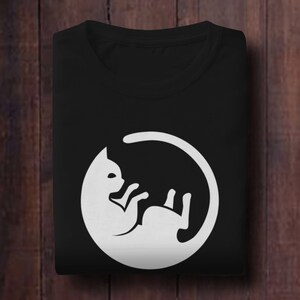 May include: Black t-shirt with a white graphic of a cat curled up in a circle.