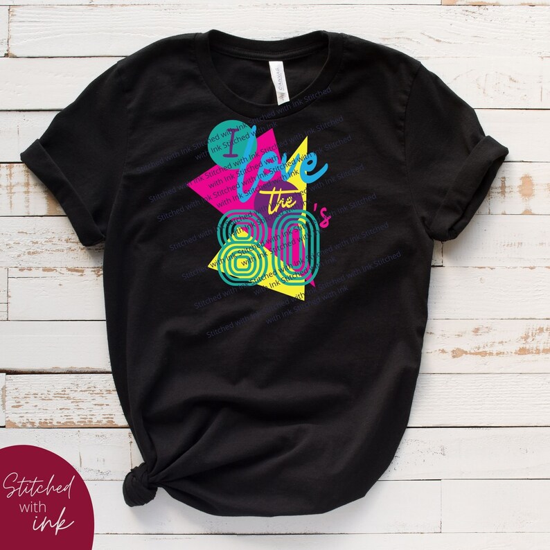 May include: Black t-shirt featuring a graphic design of a colourful geometric pattern and the text "I love the 80's".