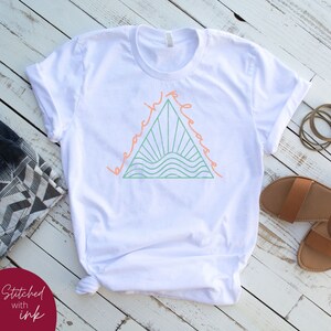 K&ouml;nnte beinhalten: Wei&szlig;es T-Shirt mit einem grafischen Design eines Dreiecks mit den Worten "beach please" darum herum. Das Dreieck enth&auml;lt eine gr&uuml;ne Sonne und Wellen.