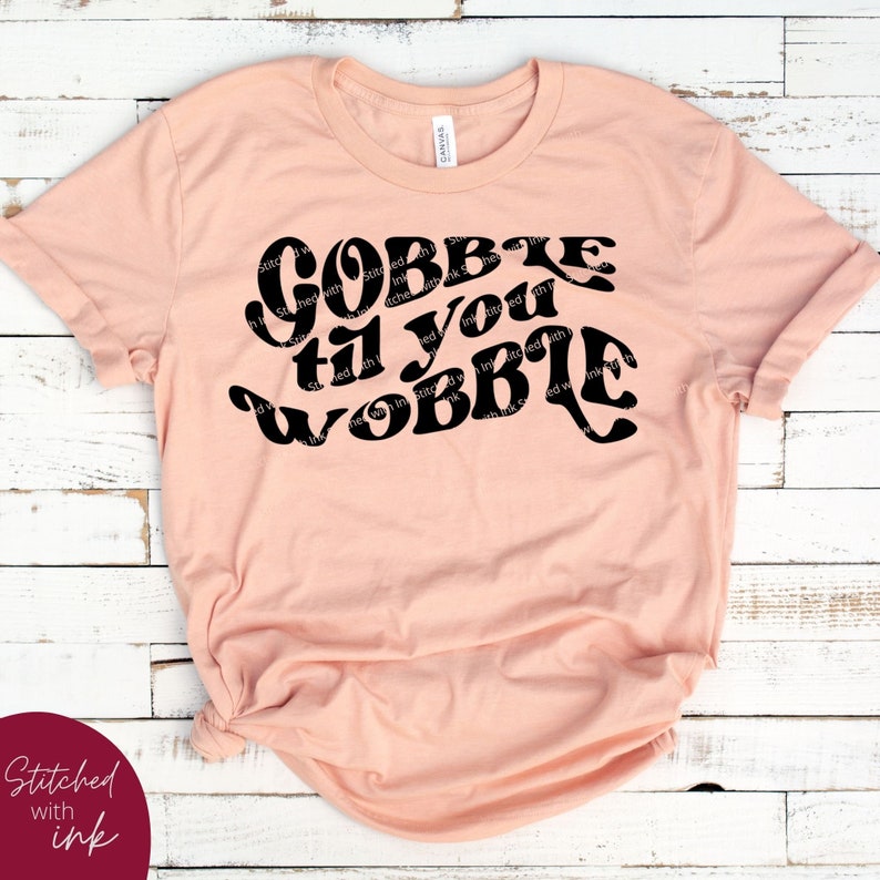 May include: A peach-colored t-shirt with the text "Gobble til you wobble" in a retro font.