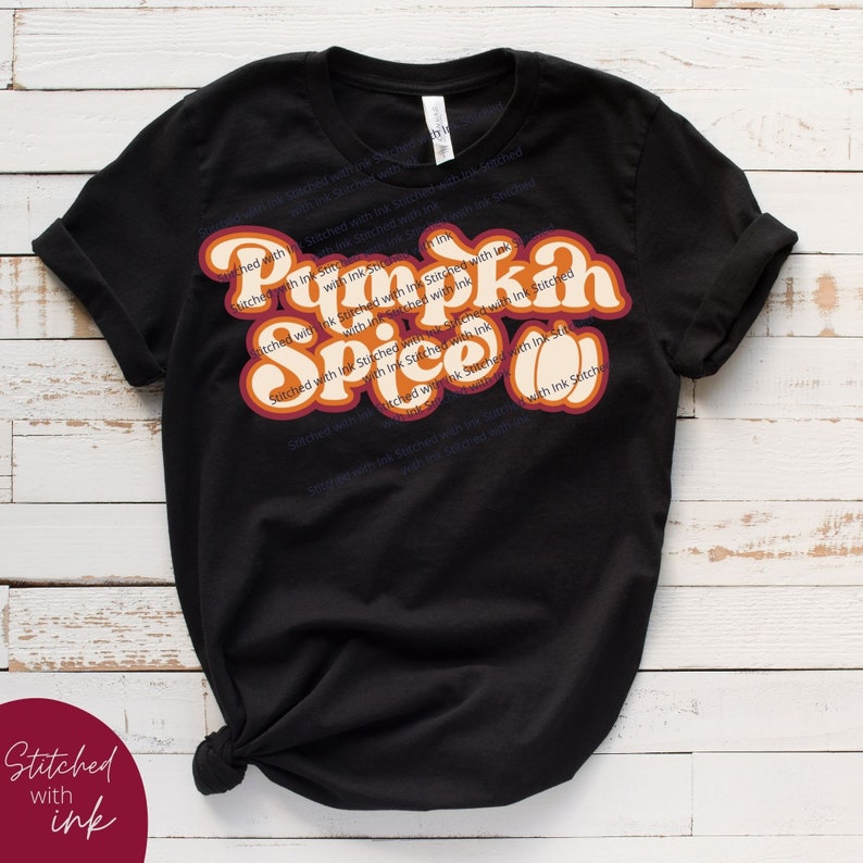 May include: Black t-shirt featuring a retro-style graphic that reads "Pumpkin Spice" in orange and yellow lettering with a brown outline. The text is layered and has a 3D effect.