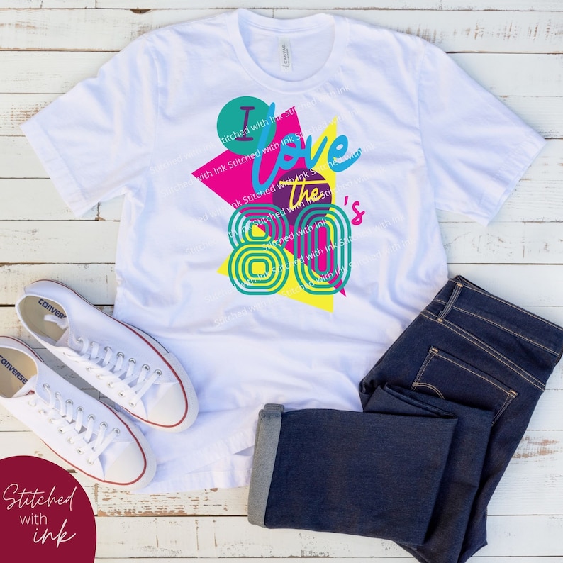 May include: White t-shirt with a graphic design featuring a colourful geometric pattern and the text "I love the 80's".