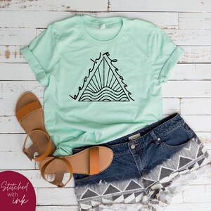 K&ouml;nnte beinhalten: Ein hellgr&uuml;nes T-Shirt mit einer schwarzen Grafik eines Dreiecks mit den Worten "beach vibes" darin. Die Grafik enth&auml;lt auch eine Sonne und Wellen.