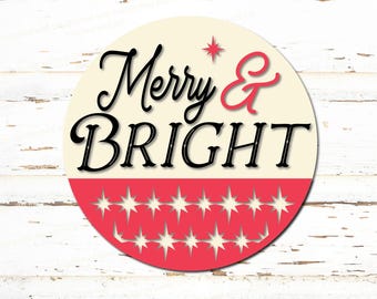 May include: A round, cream-colored sign with the text "Merry & BRIGHT" in black script font. The bottom half of the sign is red with a white starburst pattern.