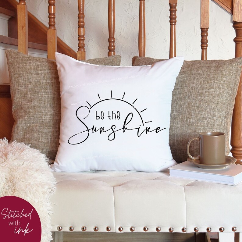 Pu&ograve; includere: Cuscino bianco con testo nero che recita "Be the Sunshine" e una grafica solare stilizzata.