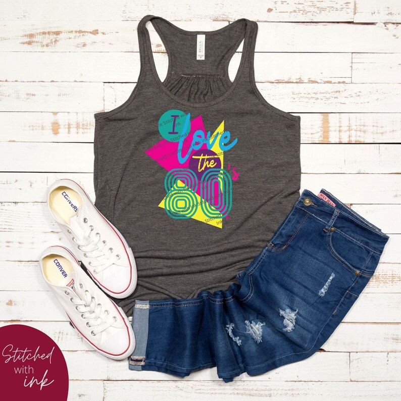 May include: A grey tank top with a graphic print of a colourful geometric design. The design features the text "I love the 80's" in a retro font.