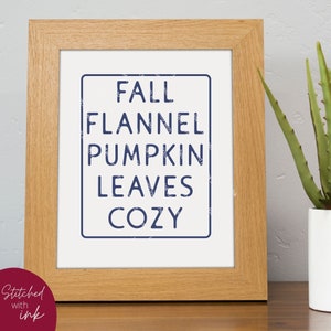 Puede incluir: Una impresi&oacute;n enmarcada con las palabras "Fall, Flannel, Pumpkin, Leaves, Cozy" en azul marino sobre un fondo blanco.