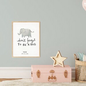 Op de afbeelding: Een ingelijst afdruk met een aquarel-illustratie van een grijze olifant met de tekst "vergeet niet aardig te zijn" en de naam "Oscar" en de datum "23 juni 2021" onder de illustratie.