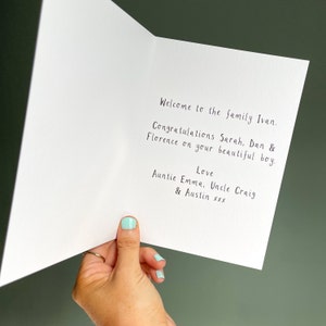 May include: A white card with a handwritten message that reads "Welcome to the family Ivan. Congratulations Sarah, Dan & Florence on your beautiful boy. Love Auntie Emma, Uncle Craig & Austin xxx"
