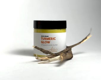 May include: A small jar of 100% vegan turmeric glow whipped body butter. The jar has a black lid and a white label with the text "100% vegan turmeric glow whipped body butter" and "Adina's Kitchen & Botanics".